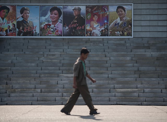 People walk past film posters as they arrive to watch a film at the Pyongyang International Cinema during the 15th Pyongyang Film Festival in the capital of North Korea on 23 September, 2016.