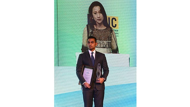 Zaraif Hossain (Front) watches his mother Simeen Hossain (Rear on screen) speaking after receiving the Mother Teresa Memorial International Award for Social Justice 2016, on behalf of her son Faraaz Ayaaz Hossain at an award ceremony in Mumbai on 20 November 2016. Photo: AFP