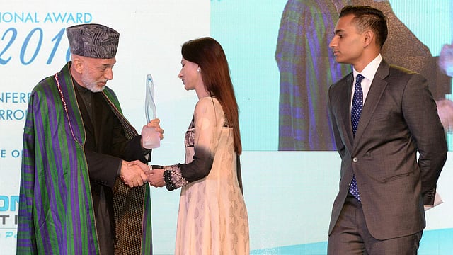 Simeen Hossain (C), escorted by her elder son Zaraif (R) receives the Mother Teresa Memorial International Award for Social Justice 2016 from former Afghan president Hamid Karzai, on behalf of her son Faraaz Ayaaz Hossain at an award ceremony in Mumbai on 20 November 2016. Photo: AFP