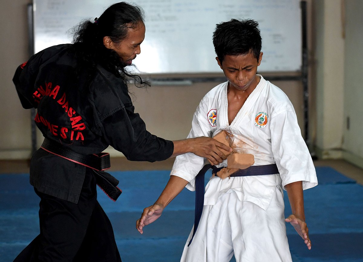This picture taken on 2 October, 2016 shows a teenaged student (R) standing his ground as he takes a blow from a brick being smashed onto his stomach during a demonstration of his `pencak silat` martial arts skills in Jakarta. Photo: AFP