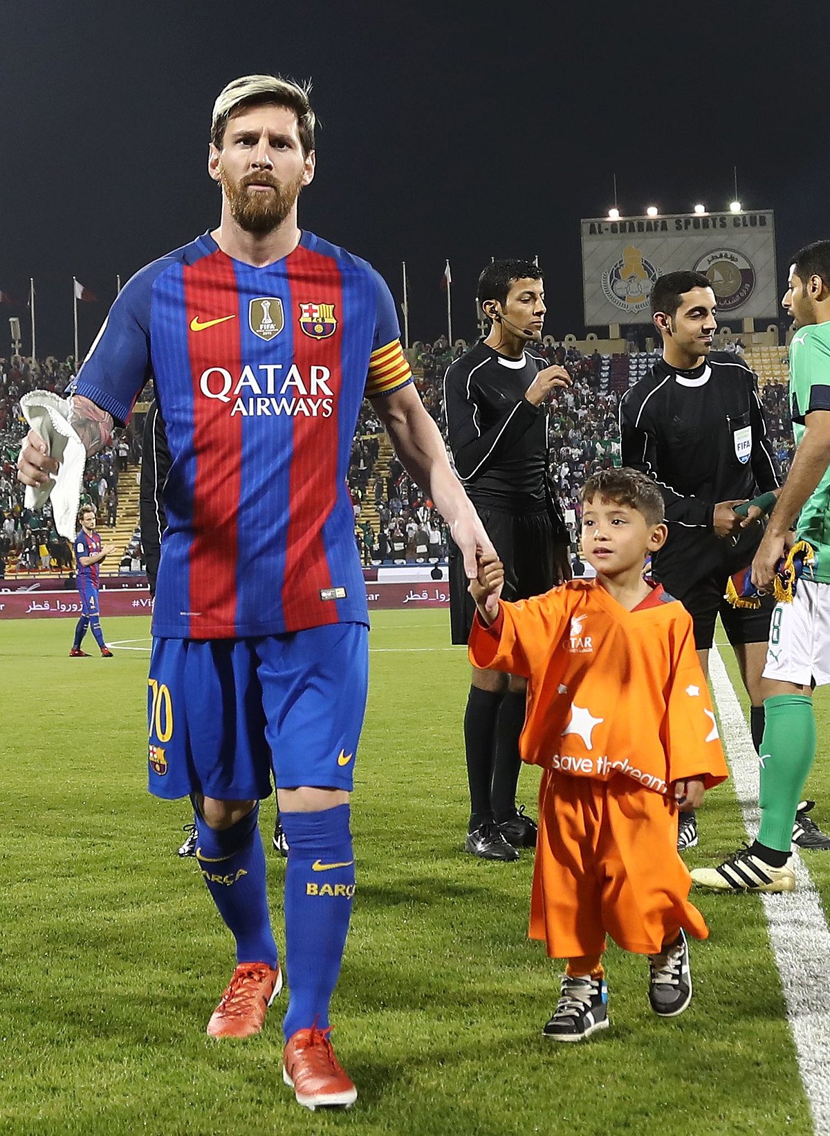 FC Barcelona Lionel Messi (L) holds the hands of Afghan boy Murtaza Ahmadi on the pitch before the start of a friendly football match against Saudi Arabia’s Al-Ahli FC. Photo: AFP