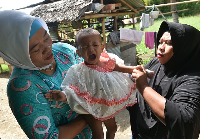 In this photograph taken on February 20, 2017, toddler Salsa Djafar (C) cries after a traditional healer conducted a circumcision in Gorontalo, in Indonesia's Gorontalo province. AFP