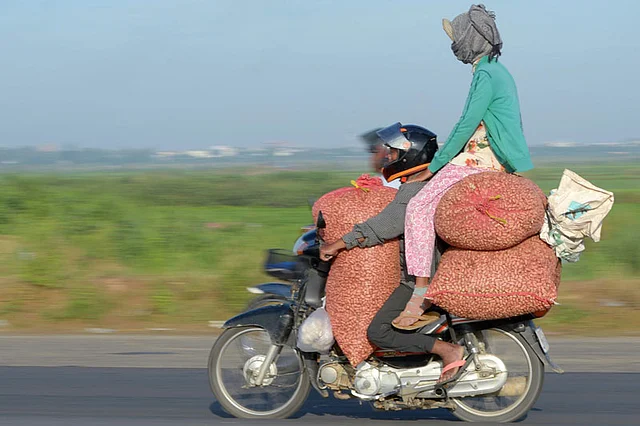 A motorcyclist ferries a pillion rider sitting on goods in Phnom Penh on June 6, 2017. AFP