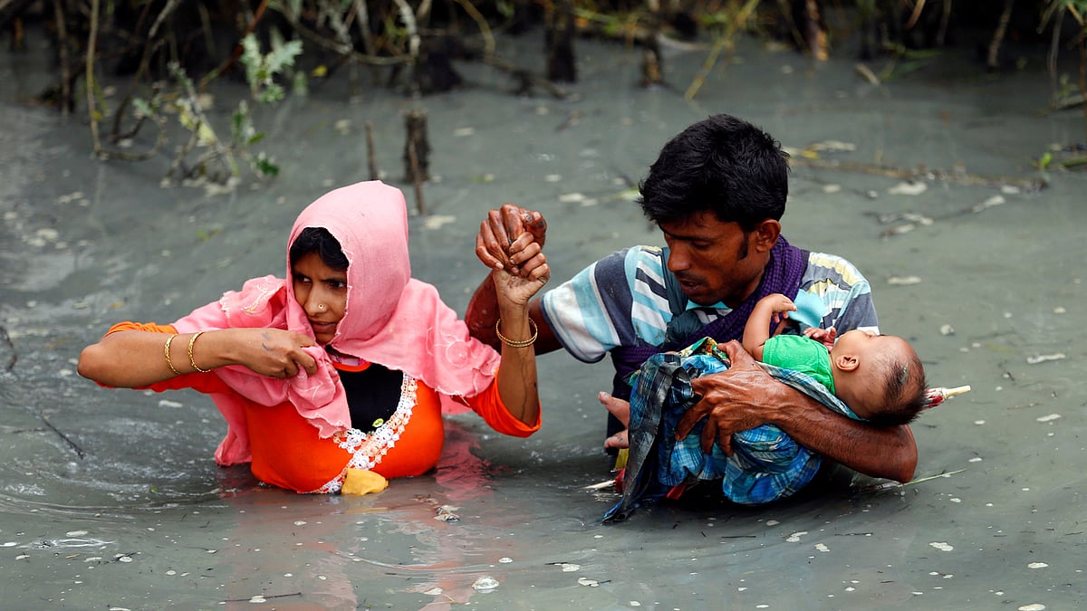 Rohingya refugees carry their child as they walk through water after crossing border by boat through the Naf River in Teknaf, Bangladesh on 7 September 2017. Photo: Reuters