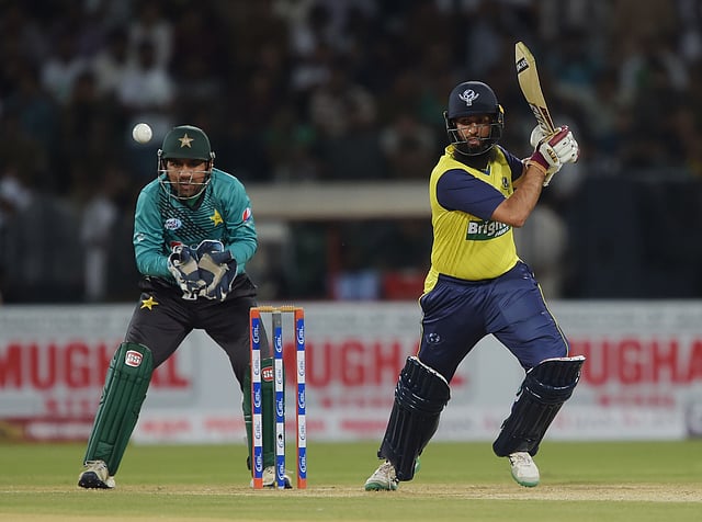 World XI batsman Hashim Amla (R) plays a shot as Pakistani captain and wicketkeeper Sarfraz Ahmad looks on during the second Twenty20 International match at the Gaddafi Cricket Stadium in Lahore on September 13, 2017. Photo: AFP