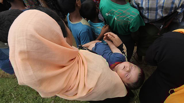 Mother stands with child under glaring sun, waiting for relief near the Balukhali camp on Wednesday. Photo: Abdus Salam