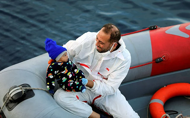 A member of a rescue team carries a migrant baby after being rescued by Libyan coast guards in the Mediterranean Sea off the coast of Libya, on 15 January. Photo: Reuters