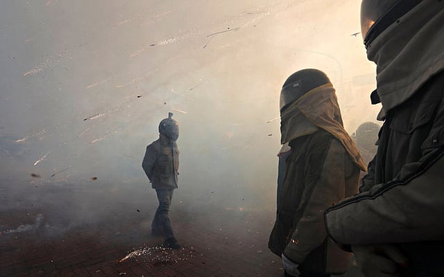 Participators wearing motorcycle helmet get sprayed by firecrackers, during `Beehive Firecrackers` festival at the Yanshui district, in Tainan, Taiwan on 1 March. Photo: Reuters