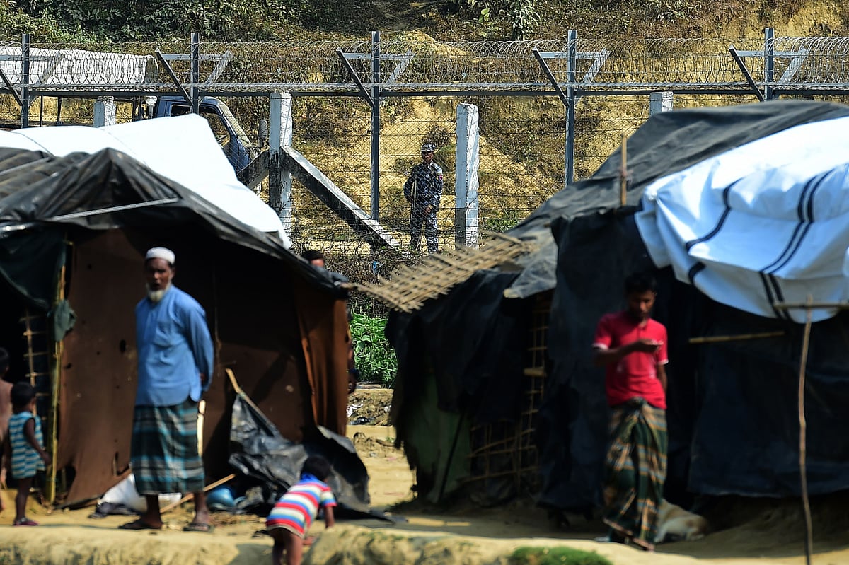 5. A Myanmar security personnel keeps watch along the Myanmar-Bangladesh border as Rohingya refugee stand outside their makeshifts shelters near Tombru, in the Bangladeshi district of Bandarban on March 1, 2018. Photo: AFP