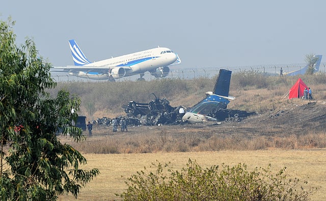 An airplane takes off at the international airport in Kathmandu on 13 March 2018, near the wreckage of a US-Bangla Airlines plane that crashed on March 12. AFP