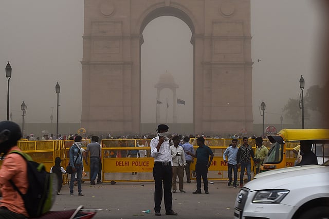 This photo taken on 2 May 2018 shows an Indian traffic policeman covering his face as he stands on duty during a dust storm in New Delhi. AFP