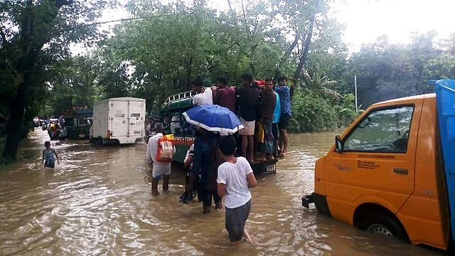 People wade through knee-deep water on a road in Raozan upazila on Tuesday. Photo: UNB