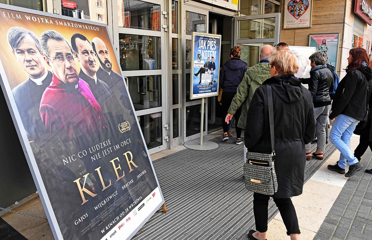 People pass by poster of movie “Kler” (The Clergy) at the entrance the cinema in Warsaw on 29 September. Photo: AFP