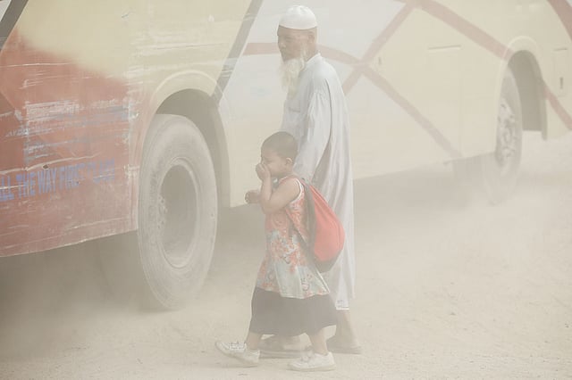 An elderly man with a child in a cloud of dust crossing the Postogola, Jatrabari road currently undergoing development. The picture was taken from Muradpur in Kadamtali, Dhaka on 8 October. Photo: Dipu Malakar