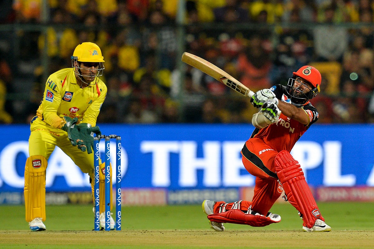 Royal Challengers Bangalore batsman Parthiv Patel (R) plays a shot while Chennai Super Kings captain M.S. Dhoni looks on during the 2019 Indian Premier League (IPL) Twenty20 cricket match between Royal Challengers Bangalore and Chennai Super Kings at the M Chinnaswamy Stadium in Bangalore on 21 April, 2019. Photo: AFP