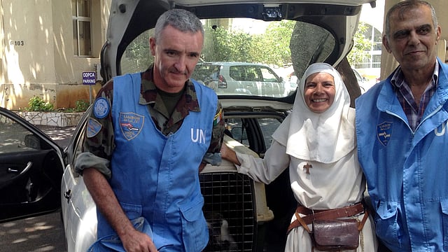 The monkey Tachtouch is pictured in a cage next to its French owner Beatrice Mauger (C) during the return voyage across the fortified border that had to be undertaken with help from the UN`s peacekeeping force UNIFIL (L and R) near Al Qouzah, southern Lebanon on 7 June. Photo: AFP