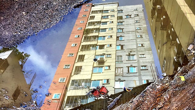 Reflection of a high-rise building in an ankle-deep puddle of water on the road near Moghbazar rail-gate, Dhaka on 23 June. Roads filled with potholes can be very dangerous for the commuters during the rainy season as rainwater fills those and makes it hard to identify. Photo: Farjana Liakat