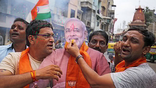 People hold a cut-out of India`s prime minister Narendra Modi as they celebrate after the government scrapped the special status of Kashmir, in Ahmedabad, India, 5 August, 2019. REUTERS