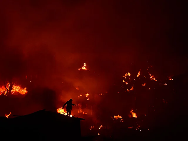 Bangladeshi man tries to extinguish a fire as a fire blazes in a slum in Dhaka on 16 August 2019. Photo: AFP