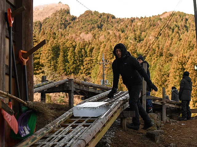 This picture taken on 10 January 2019 shows a worker sliding a block of natural ice on a bamboo rail after it was cut from an open-air pool at a factory in Nikko, Tochigi prefecture. Photo: AFP