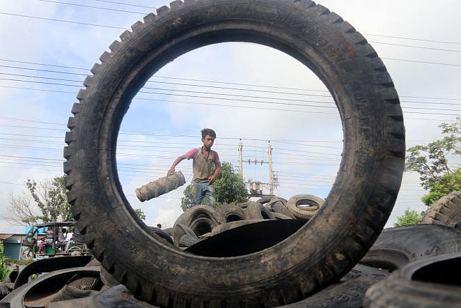 A teenage boy works in the pile of old tyres in Laskarpur, Pabna on 8 September, 2019. Photo: Hasan Mahmud