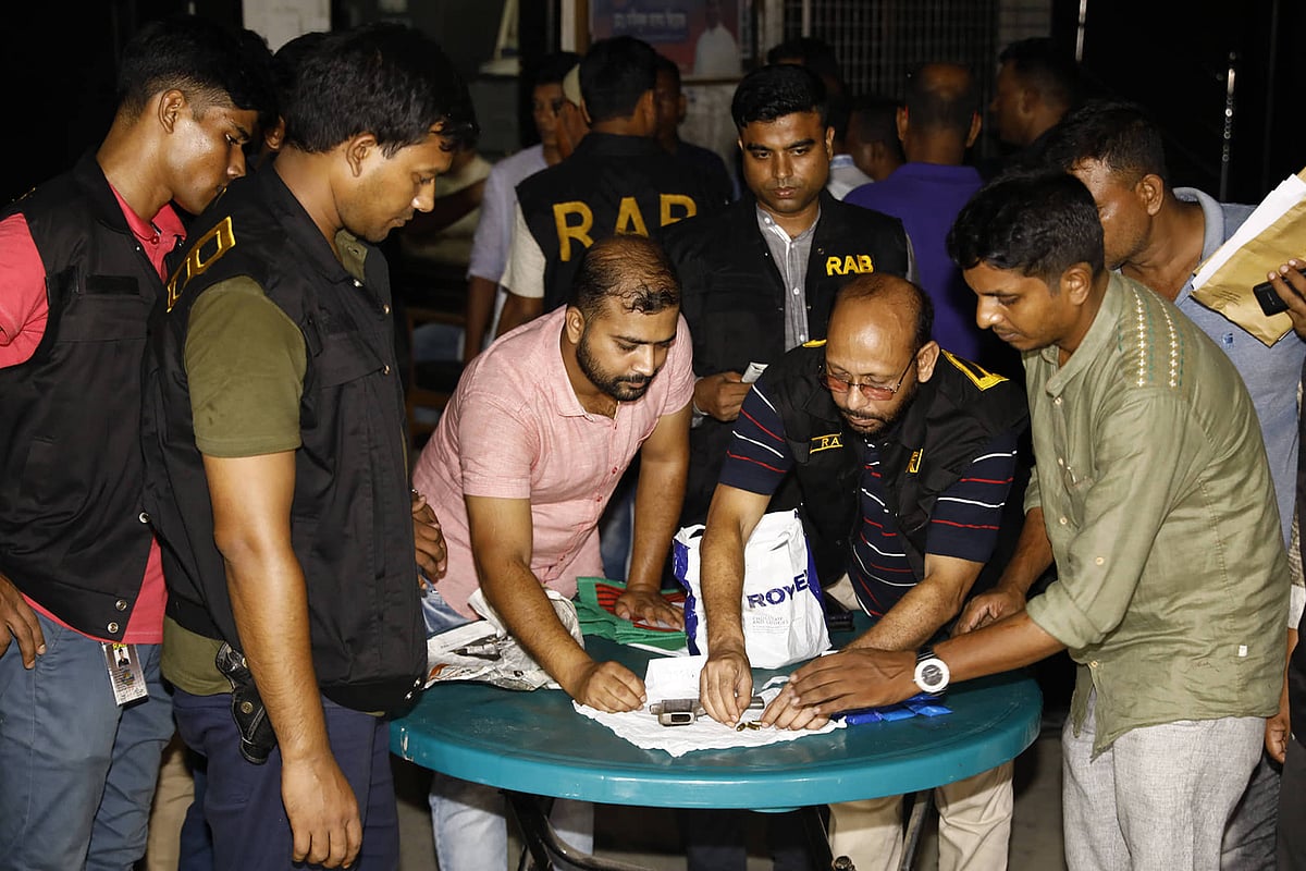 RAB men oversee the coins used in gambling, 572 packets of cards, a foreign-made pistol, bullets and yaba pills they have recovered from Kalabagan Krira Chakra’s office on 20 September, 2019. Photo: Shuvra Kanti Das