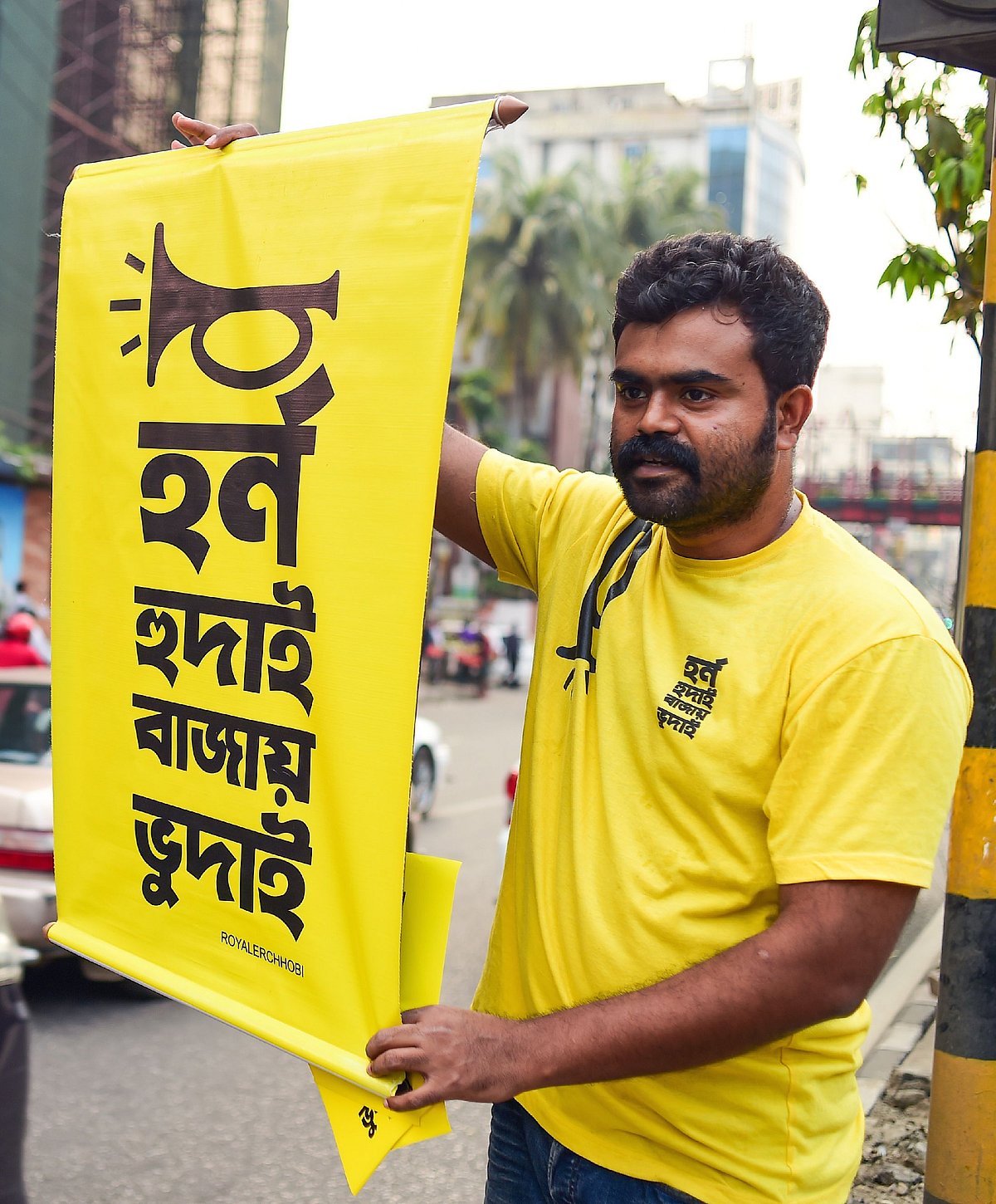 In this photo taken on 22 March 2019, Mominur Rahman Royal holds a banner with a Bengali slogan -- `Horn hudai, Bajay Bhudai` that translates to `only the idiot honks horn unnecessarily` -- on a busy street in Dhaka. Photo: AFP