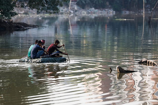 People cross Gulshan Lake in Dhaka on a raft made of bottles and cock sheets on 14 December 2019. Photo: Dipu Malakar