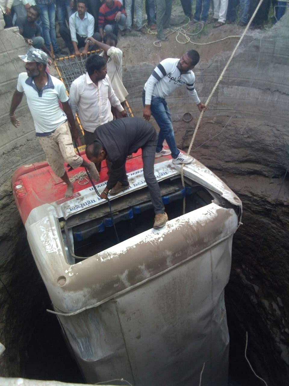 This handout photo taken on 28 January and released by the National Disaster Response Force (NDRF) shows rescue workers gathering around the remains of a bus that fell into a well after crashing with an autorickshaw at Meshi Phata on the Malegaon Deola Road in Maharashtra`s Nashik district. Photo: AFP