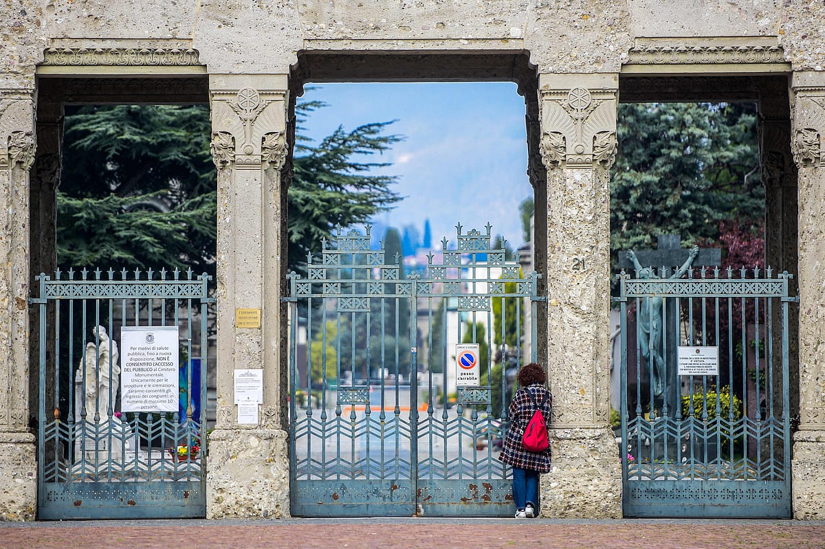 A woman looks inside the closed Monumental Cemetery of Bergamo, Lombardy, on 20 March 2020 during the country's lockdown aimed at stopping the spread of the COVID-19 pandemic.