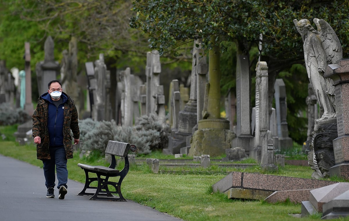 A man wearing a protective face mask is seen in a cemetery, as the spread of the coronavirus disease (COVID-19) continues, London, Britain, 28 March 2020.
