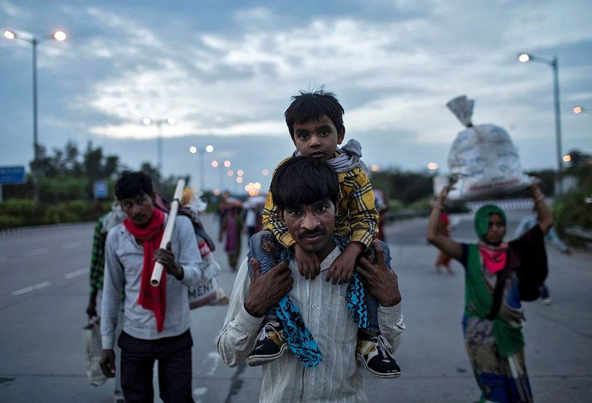 A migrant worker carries his son as they walk along a road with others to return to their village, during a 21-day nationwide lockdown to limit the spreading of coronavirus disease (COVID-19), in New Delhi, India, 26 March 2020.