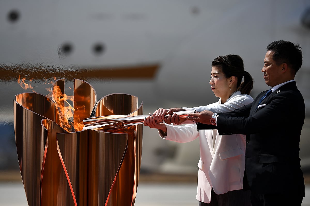 Japanese three-time Olympic gold medallists Saori Yoshida (L) and Tadahiro Nomura (R) light a Tokyo 2020 Olympic cauldron with the Olympic flame, after transporting the flame from Greece, at the Japan Air Self-Defense Force Matsushima Base in Higashimatsushima, Miyagi prefecture on 20 March 2020