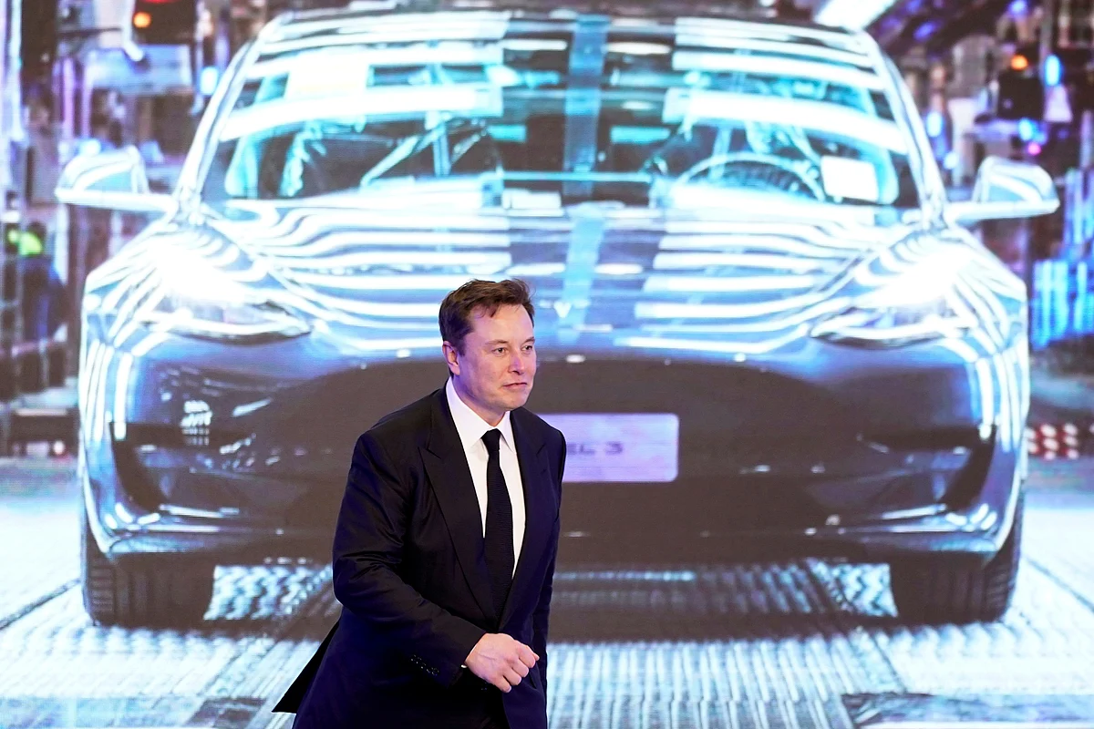 Tesla Inc CEO Elon Musk walks next to a screen showing an image of Tesla. Photo: Reuters