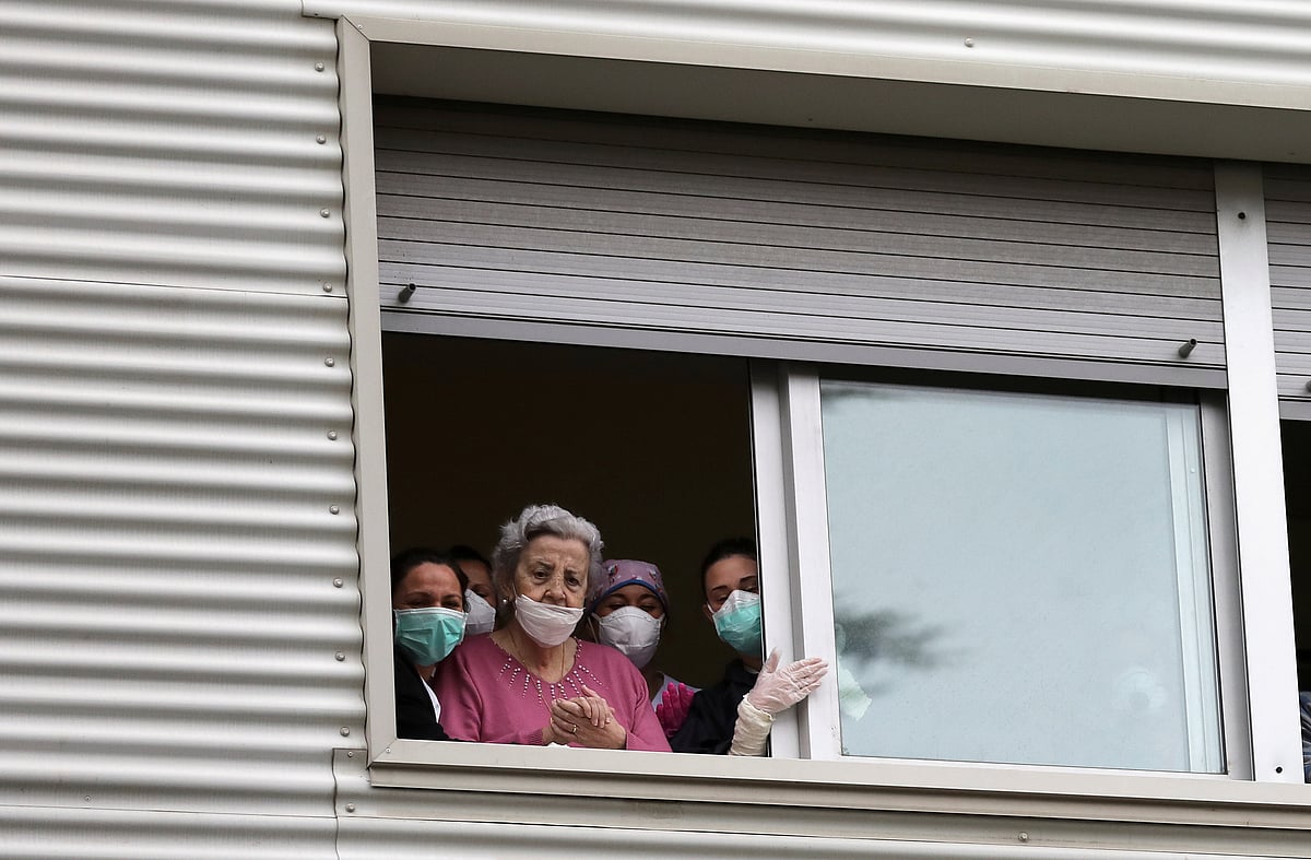 Concepcion Espinar, 85, and medical workers look out from the window of the Ramon Berenguer nursing home in Santa Coloma de Gramenet, during the coronavirus disease (COVID-19) outbreak, outside Barcelona, Spain, 1 April 2020.