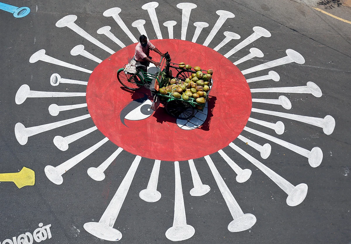 A man selling coconuts rides his trishaw on a graffiti on a road depicting the coronavirus as an attempt to raise awareness about the importance of staying at home during a 21-day nationwide lockdown to slow the spreading of the coronavirus disease (COVID-19), in Chennai, India, April 13, 2020. R