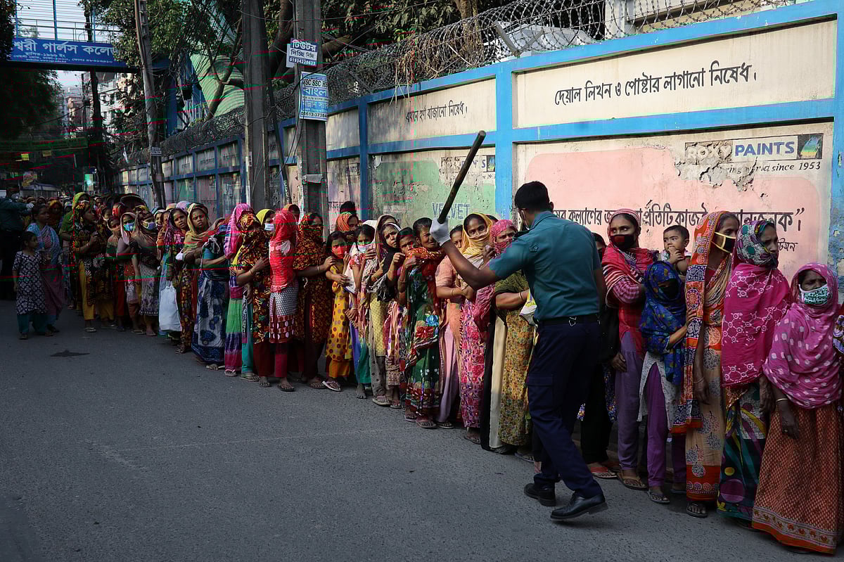 A policeman wields his baton as he tells to people to stay in the queue in order to receive relief supplies provided by local community amid the coronavirus disease (COVID-19) outbreak in Dhaka, Bangladesh, on 1 April 2020