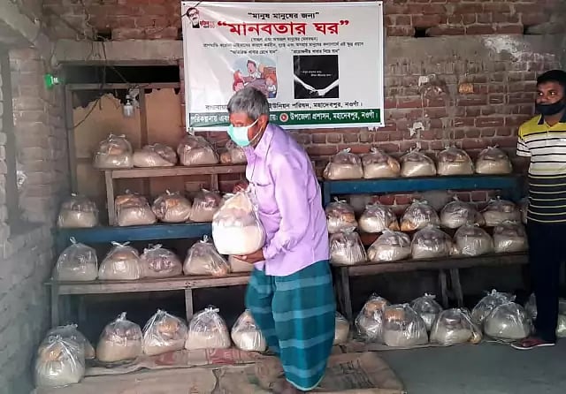 An elderly person taking a packet of food from Mohadebpur’s Home of Humanity on Sunday.