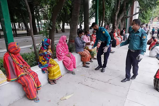 Police distribute food among low income people at Victoria Park in Dhaka on 15 April.