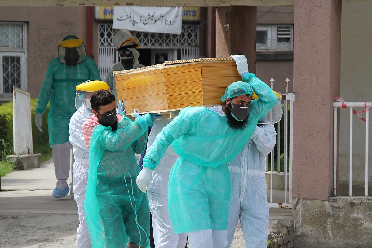 Health workers wearing protective gear move a body of a man who died from the coronavirus disease in Abbottabad, Pakistan on 16 April.