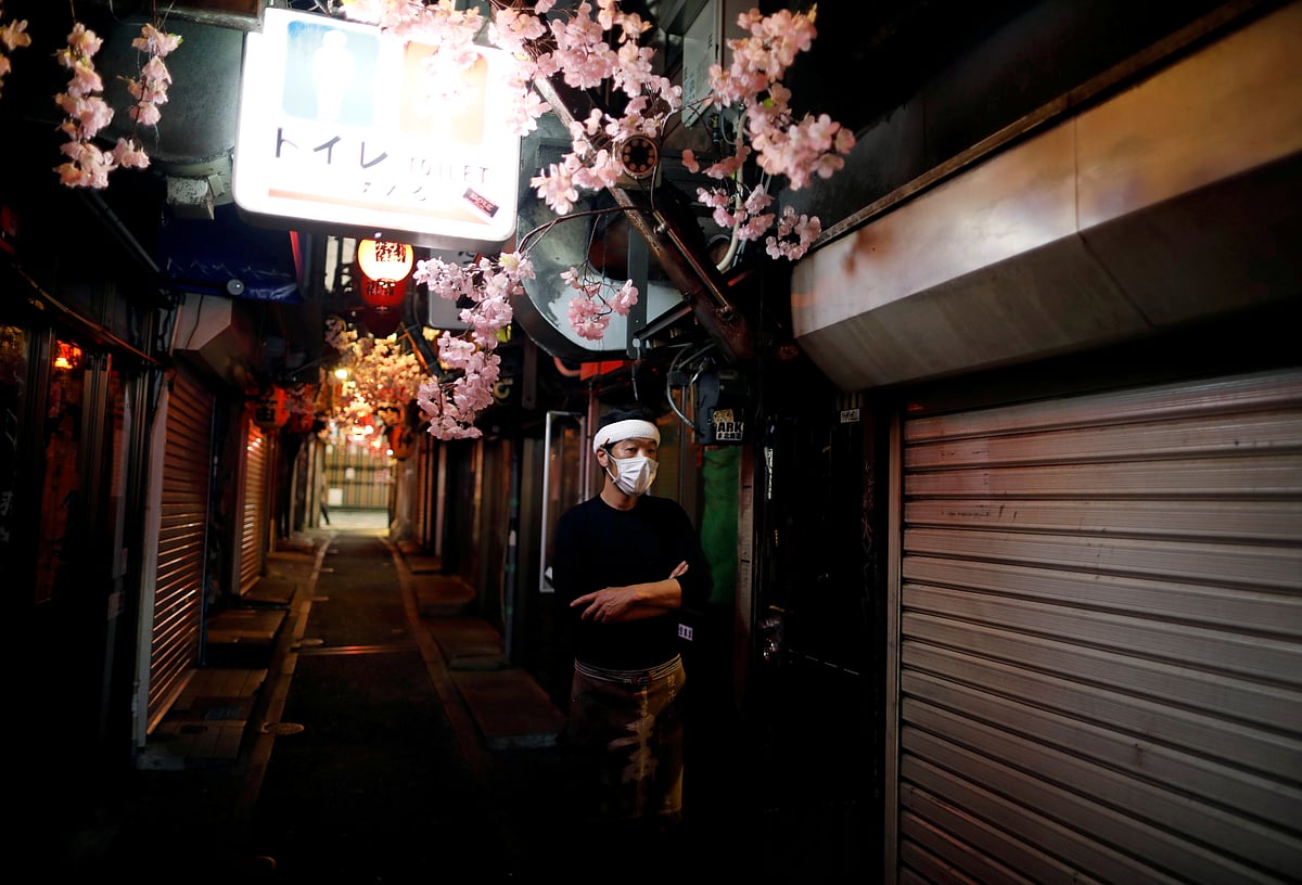 A staff member of a restaurant wearing a protective face mask stands along a Japanese at Shinjuku district in Tokyo, Japan 8 April 2020.