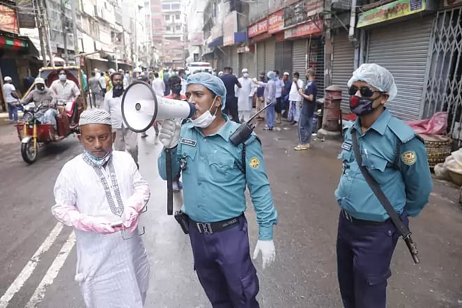 A member of police using hand-mike announces social distancing rules to aware people amid coronavirus outbreak at Bangshal, Dhaka on 25 April 2020.