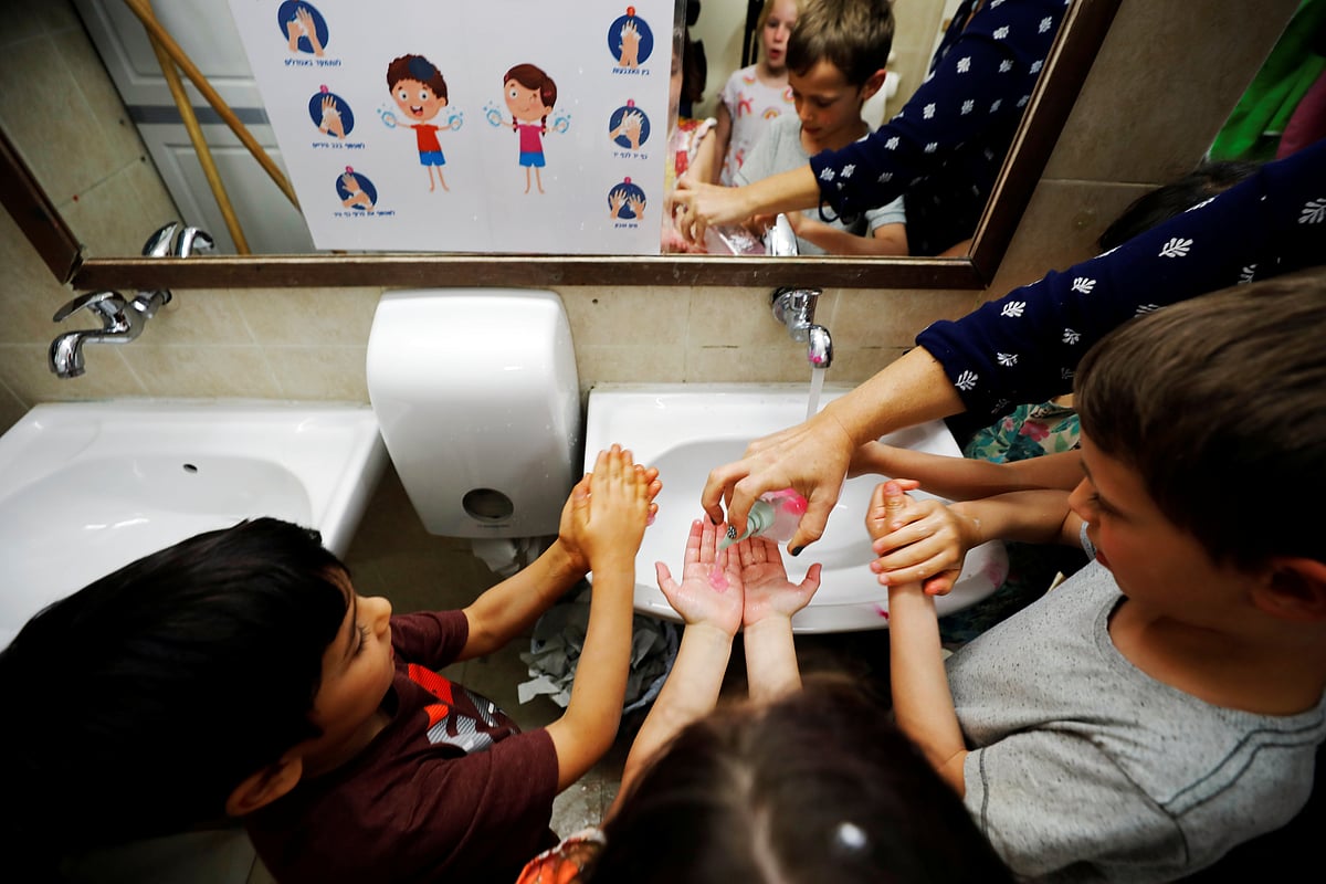 Teacher shows children how to wash their hands at her kindergarten in Jerusalem.