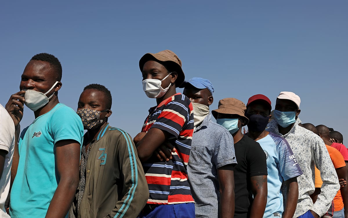 People wearing protective face masks stand in a queue to receive food aid amid the spread of the coronavirus disease (COVID-19) outbreak, at the Itireleng informal settlement, near Laudium suburb in Pretoria, South Africa on 20 May.