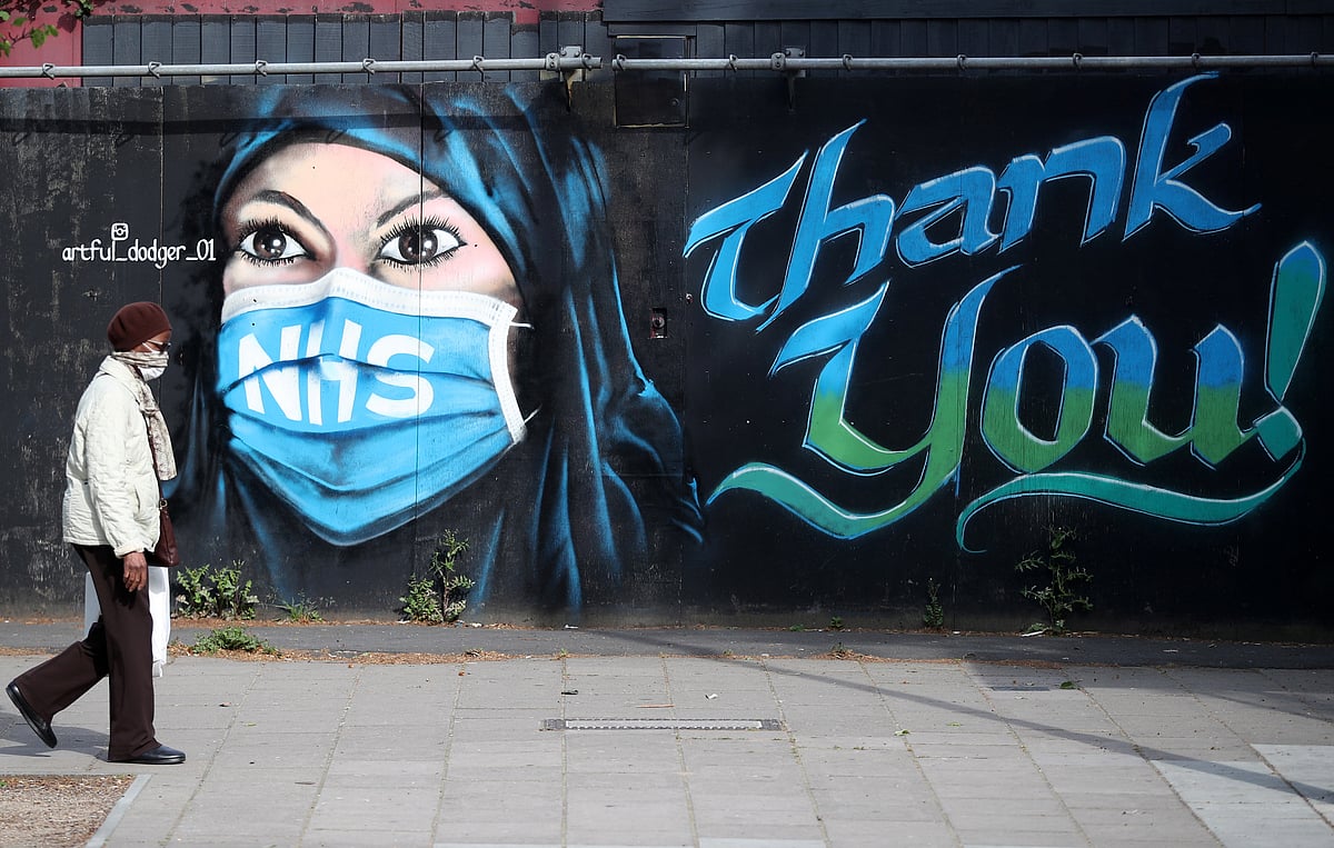 A person wearing a protective face mask walks past streetart ‘NHS Dedication Mural’ by The Artful Dodger (A.Dee) in Elephant & Castle, following the outbreak of the coronavirus disease (COVID-19), London, Britain, 5 May 2020.