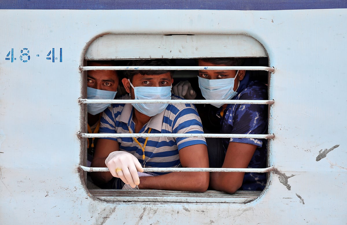 Migrant workers wear protective masks as they look out from a window of a train upon their arrival in their home state of eastern West Bengal, India, 5 May 2020.