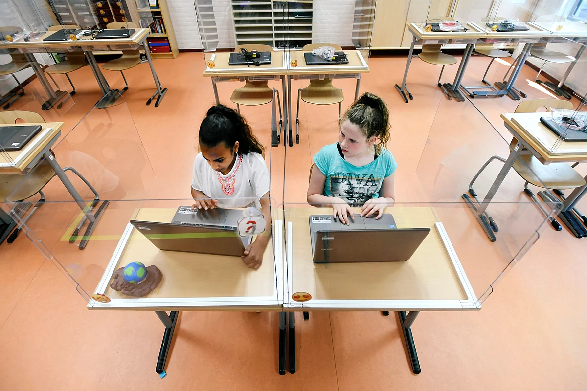 Pupils sitting behind partition boards made of plexiglass attend a class at a primary school, during the coronavirus disease (COVID-19) outbreak, in Den Bosch, Netherlands, on 8 May 2020