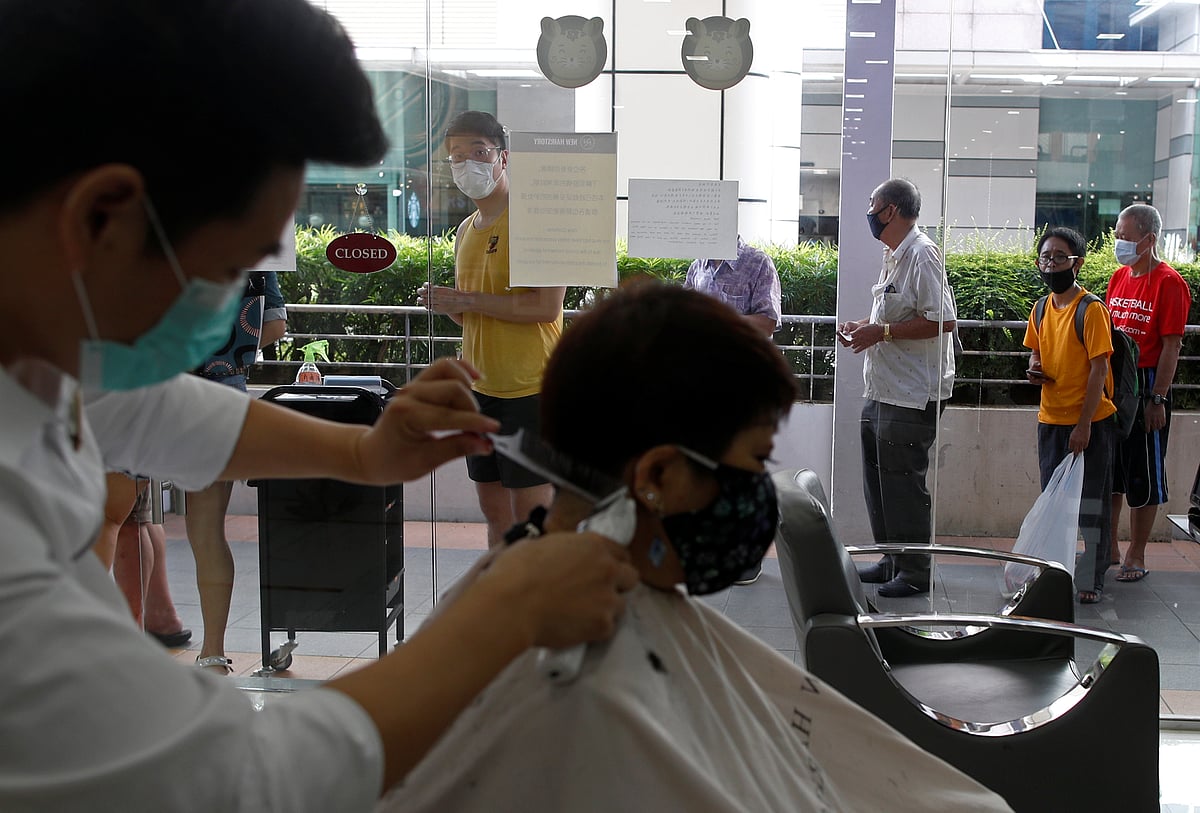 Customers queue up to have their haircut outside a hairdressing salon as they reopen for business amid the coronavirus disease (COVID-19) outbreak in Singapore 12 May 2020.