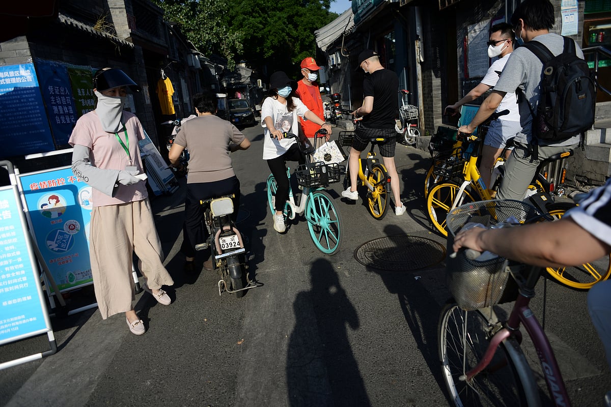 A woman holds a thermometer at a checkpoint set up at an entrance to a hutong, following new cases of the coronavirus disease (COVID-19) infections, in Beijing, China on 16 June 2020.