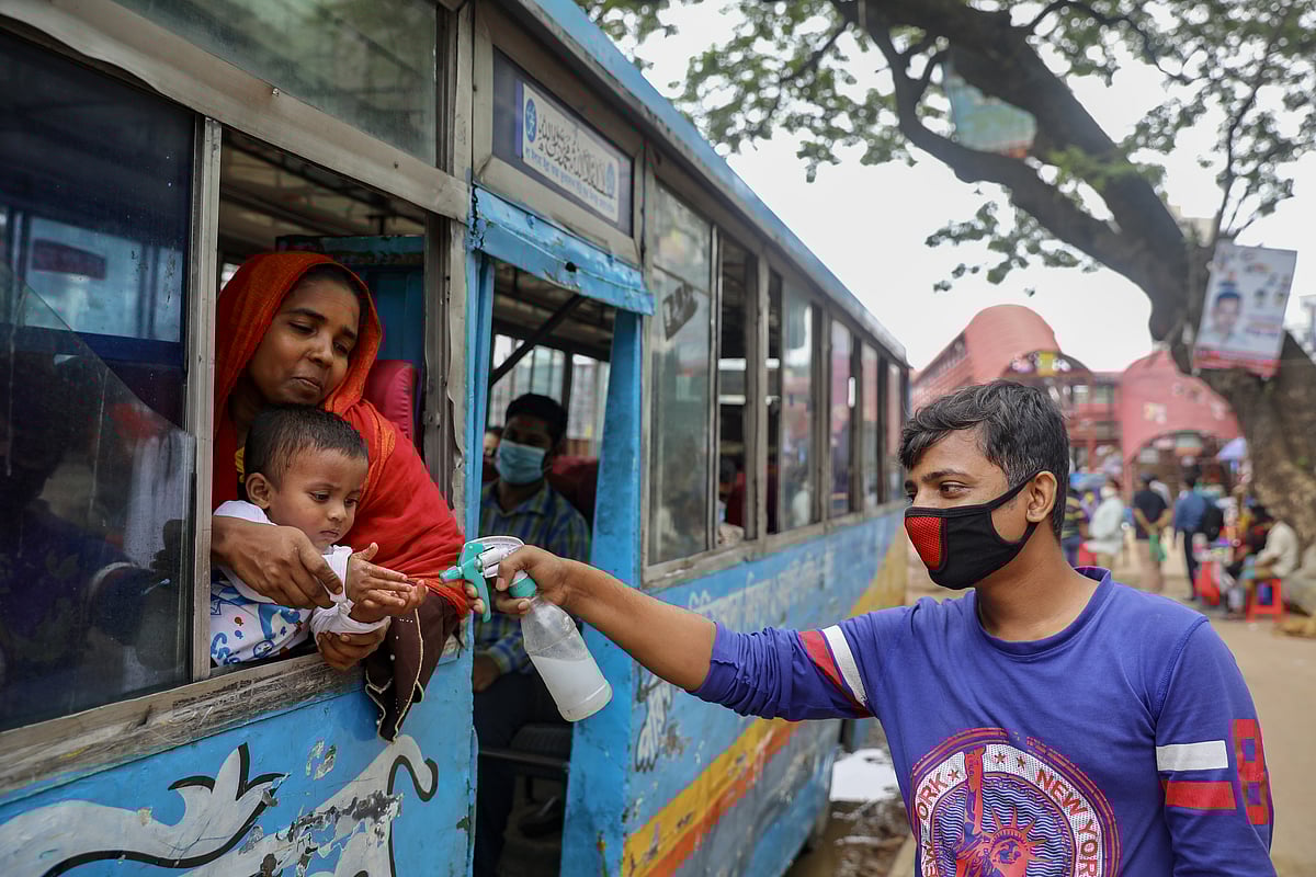 A man sprays hand sanitiser to a child who is traveling on a public bus amid the coronavirus disease (COVID-19) outbreak in Dhaka, Bangladesh, 22 June 2020